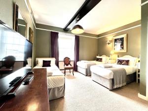 a hotel room with two beds and a desk at Colthrop Manor B&B in Thatcham