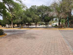 an empty parking lot with trees and a street at Motel los Alpes in Ciudad Acuña