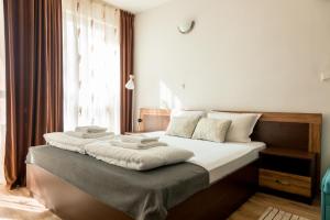 a bedroom with a bed with white sheets and a window at Студио 3 Слънчево Утро in Hisarya