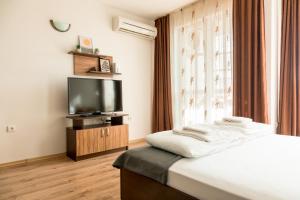 a hotel room with a bed and a flat screen tv at Студио 3 Слънчево Утро in Hisarya