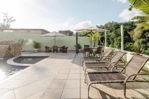 a patio with chairs and umbrellas and a pool at Pousada Queiroz in Barra da Tijuca
