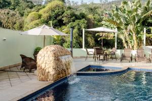 a swimming pool with a fountain in the middle at Pousada Queiroz in Barra da Tijuca