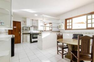 a white kitchen with a table and chairs in it at Pousada Queiroz in Barra da Tijuca