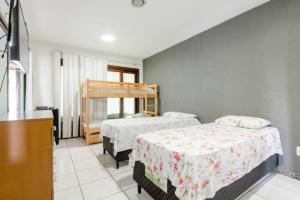 a bedroom with two beds and a tv in it at Pousada Queiroz in Barra da Tijuca