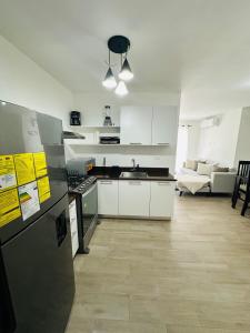 a kitchen with white appliances and a living room at Residencia tropical jardines 3 in Punta Cana