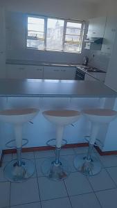 a kitchen with two bar stools in front of a counter at white house Bluewaterbay in Gqeberha +14 photos