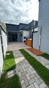 a house with a brick walkway next to a building at Beautiful Cozy Beach House Accommodation in Guaratuba