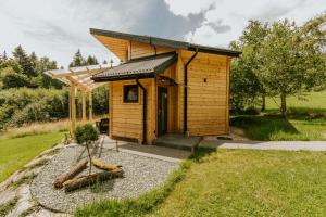 a small wooden building with a roof on a field at Cisza Traw in Rabka-Zdroj