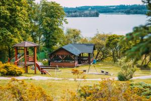 a gazebo and a playground next to a lake at Ośrodek Wypoczynkowy Sielawa in Chrzypsko Wielkie