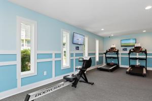 a gym with blue walls and tread machines and windows at Pebble Beach I305 by Emerald Isle Realty in Emerald Isle