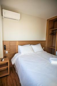 a bedroom with a white bed and a night stand at Vektor Itabirito in Itabirito
