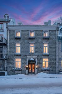a large brick building with a sunset in the background at Hotel Manoir D'Auteuil - Par Aneyro in Quebec City