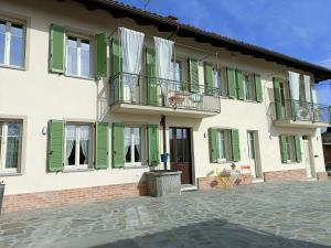 a house with green shutters and a patio at B&B Barba Vigin in San Damiano dʼAsti
