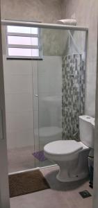 a bathroom with a toilet and a glass shower at Kitnet Moderna com Ar e Vaga Privativa Coberta in Votorantim