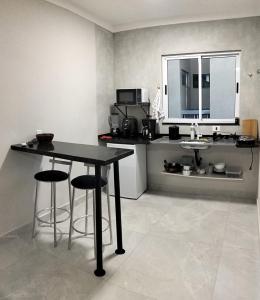 a kitchen with a table and two bar stools at Kitnet Moderna com Ar e Vaga Privativa Coberta in Votorantim