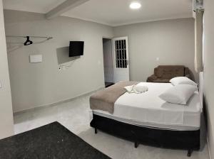 a bedroom with a large bed and a couch at Kitnet Moderna com Ar e Vaga Privativa Coberta in Votorantim
