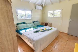 a bedroom with a large bed with two windows at Kaz KOKOYE in Baie-Mahault