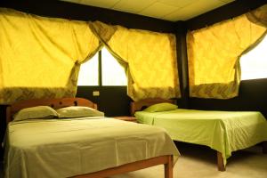 two beds in a room with yellow curtains at Johmer EXPEDITION Lodge in Islas Tinicuro