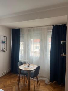 a table and chairs in a room with blue curtains at Apartman Lena in Belgrade