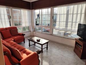 a living room with a couch and a tv and windows at Airtegal Casa da Praia Cedeira in Cedeira