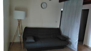 a couch in a living room with a clock on the wall at Le Gîte de Mayac,16 rue du four à pain, 24600 VILLETOUREIX FRANCE in Villetoureix
