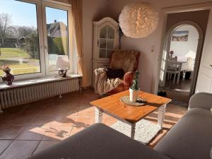 a living room with a table and a chair at Haus Ruhewinkel, Bungalow 2 in Alkersum +10 photos