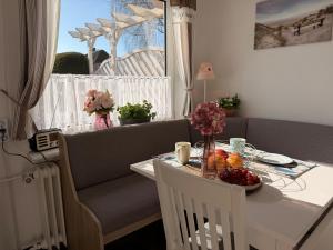 a living room with a table and a couch at Haus Ruhewinkel, Bungalow 2 in Alkersum