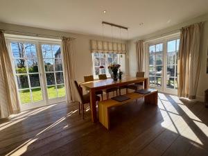 a dining room with a table and chairs and windows at Salig Hüs in Kampen