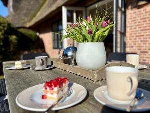 a table with a piece of cake and a vase with flowers at Salig Hüs in Kampen