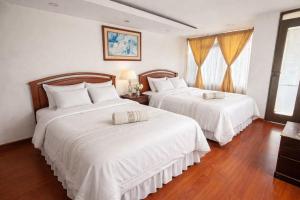a bedroom with two beds with white sheets and wood floors at Hotel Dinastia in Ipiales