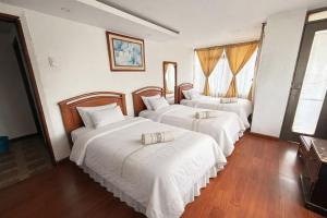 a bedroom with three beds with white sheets at Hotel Dinastia in Ipiales