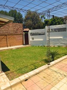 a yard with a white house and a grassy field at Casa con Jardín in Cochabamba