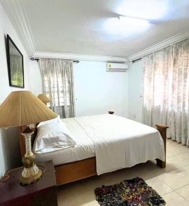 a bedroom with a bed and a lamp on a table at Aburi Emerald Garden Retreat in Aburi