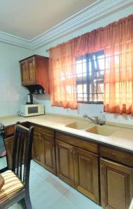 a kitchen with wooden cabinets and a sink and a window at Aburi Emerald Garden Retreat in Aburi
