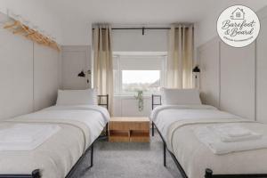 two beds in a room with a window at Contractor friendly 3BDR Home | Parking for Vans in Salford