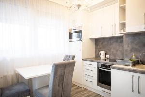a kitchen with white cabinets and a table and chairs at City Square, center in Subotica