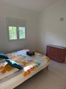 a bedroom with a bed and a dresser and a window at La jolie Villa in Le Lamentin +2 photos