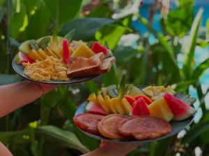 a person holding up two plates of food at Hotel Good Life in Coco