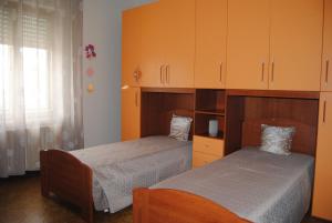 two beds in a bedroom with orange cabinets at A&M House in Vignanello +14 photos