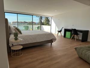 a bedroom with a large bed and some chairs at Loft Azeméis in Oliveira de Azemeis