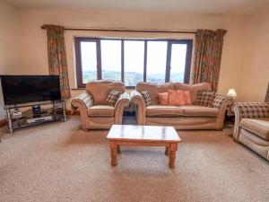 a living room with couches and a flat screen tv at Ghyll Bank House in Staveley