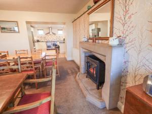 a living room with a fireplace and a dining room with a table at Ghyll Bank House in Staveley