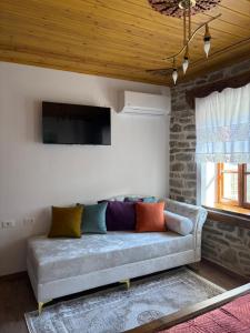 a couch sitting in a living room with a tv at Stone Pazar Guest House in Gjirokastër