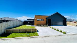 a house with a black roof and a yard at Taupo Premium Retreat - Private Spa & Ensuite in Taupo