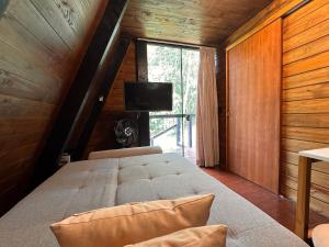 a bedroom with a bed in a room with a window at Romantic chalet with hot tub, fireplace, and view in São Pedro de Alcântara
