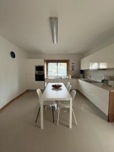 a white kitchen with a white table and chairs at Alojamento Local Pando in Vila do Conde