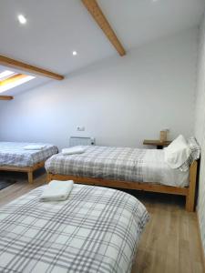 two beds in a room with white walls and wooden floors at Casa dos Cantares in Padrón