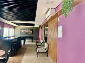 a bar in a restaurant with purple walls and chairs at Garden 2 quartos com churrasqueira in Bauru