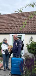 a man and woman standing in front of a house with luggage at Charming Old Cottage for Share, Cosy Double Room with 2 Single Bed in Edinburgh