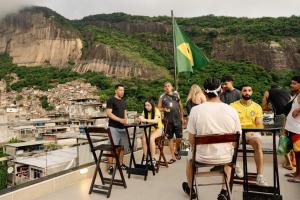 a group of people standing on a balcony with a flag at Favela Hostel in Rio de Janeiro